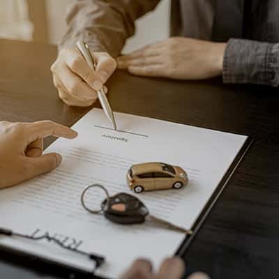 Close up view of a man signing car loan documents