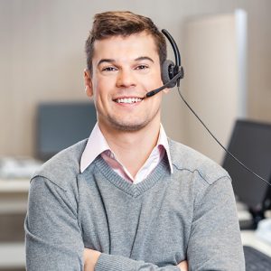 A smiling male employee wearing a headset while facing the camera in the office