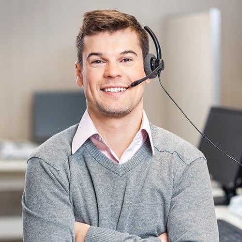 A smiling male employee wearing a headset while facing the camera in the office